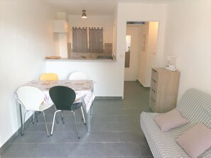 Un espacio habitable compacto con zona de comedor, kitchenette y sofá.