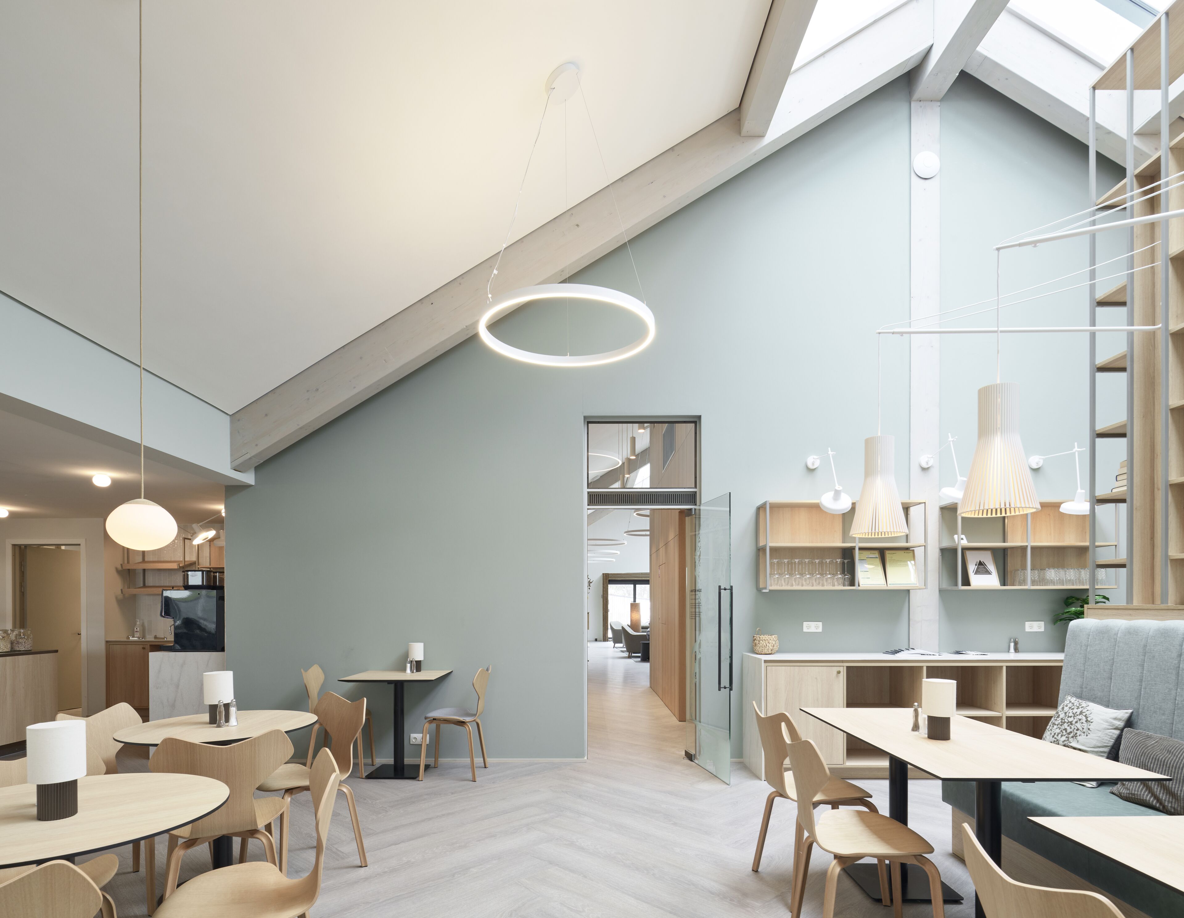 A modern interior with a dining area, kitchen, and a loft space with a skylight.