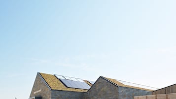 A building with a sloped roof featuring solar panels, stone walls, and a visible entrance.