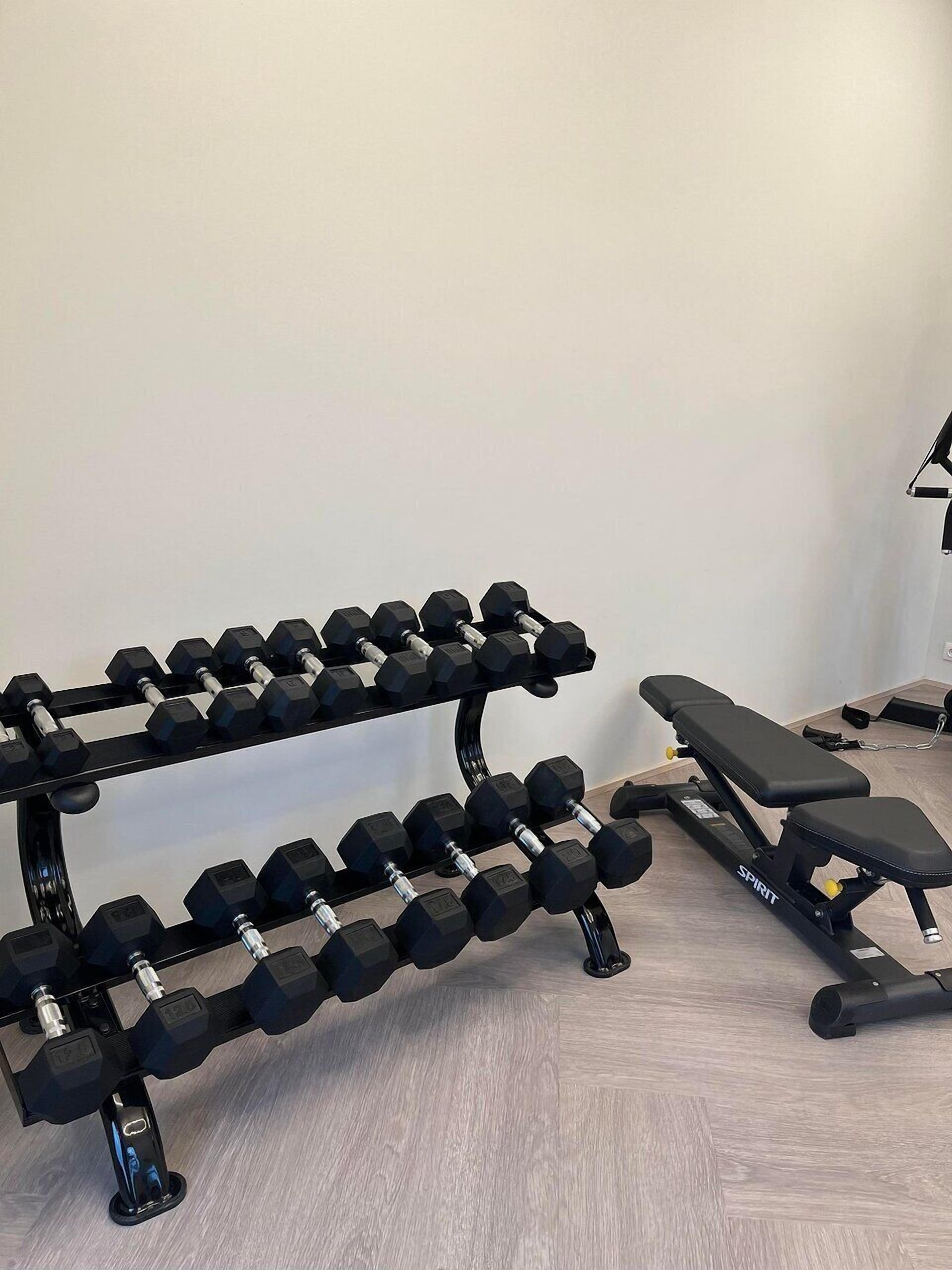 A home gym with a bench and a rack of dumbbells.