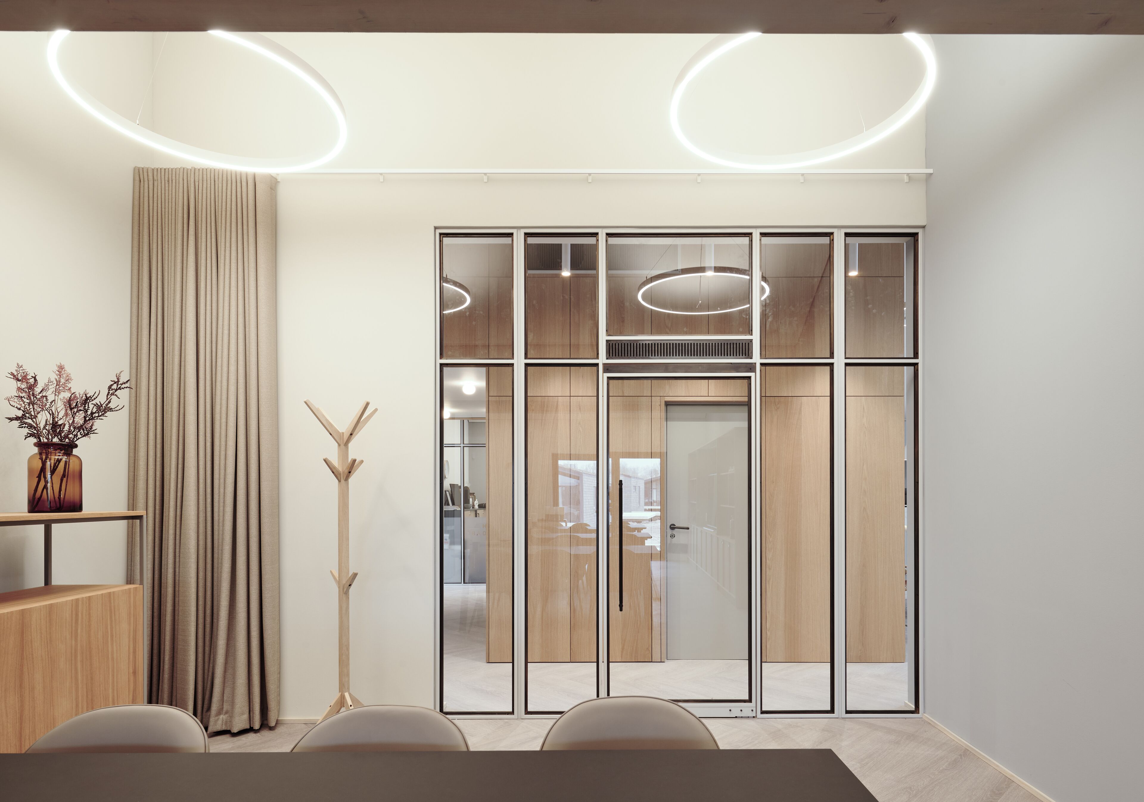 A modern meeting room with a large table, chairs, a tall floor lamp, and a sliding glass door leading to another room.