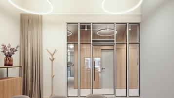 A modern meeting room with a large table, chairs, a tall floor lamp, and a sliding glass door leading to another room.