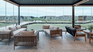 A modern, open-plan living area with a large glass wall offering views of a distant landscape.