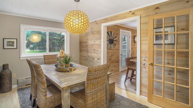 Un coin repas avec une table en bois, des chaises en osier et un luminaire suspendu.