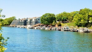 Un port de plaisance avec des bateaux amarrés, un grand bâtiment doté de nombreux balcons et, au fond, une végétation luxuriante.