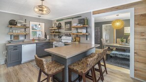 Une cuisine moderne avec des meubles de couleur grise, un îlot central en bois et des tabourets de bar.