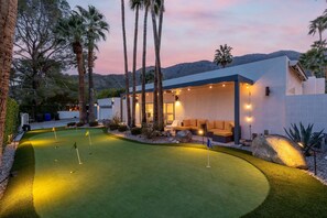 A modern house with a pool, outdoor seating, and a well-lit patio area.