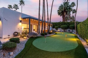A modern house with a well-maintained lawn and a golf putting green.