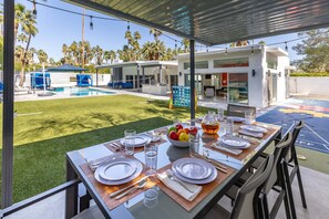 A dining area with a table set for four, outdoor pool, and modern architecture.