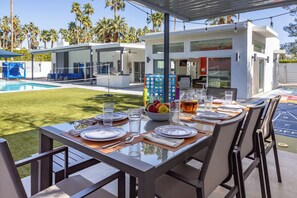 A dining area with a pool view, modern architecture, and outdoor seating.