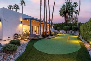 A modern house with a well-maintained lawn and a golf putting green. - Far Far Away in Vista Las Palmas–Resort Pool Home (Palm Springs)
