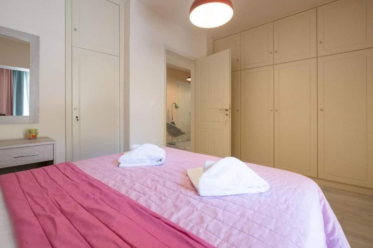 A bedroom with a bed, a nightstand, a mirror, and a wardrobe.