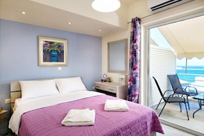 Un dormitorio con cama, cómoda, espejo y vistas al balcón con sillas.