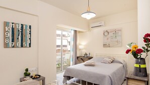 A bedroom with a bed, bedside table, lamp, and a wall clock. - Melina Apartments (Chania)