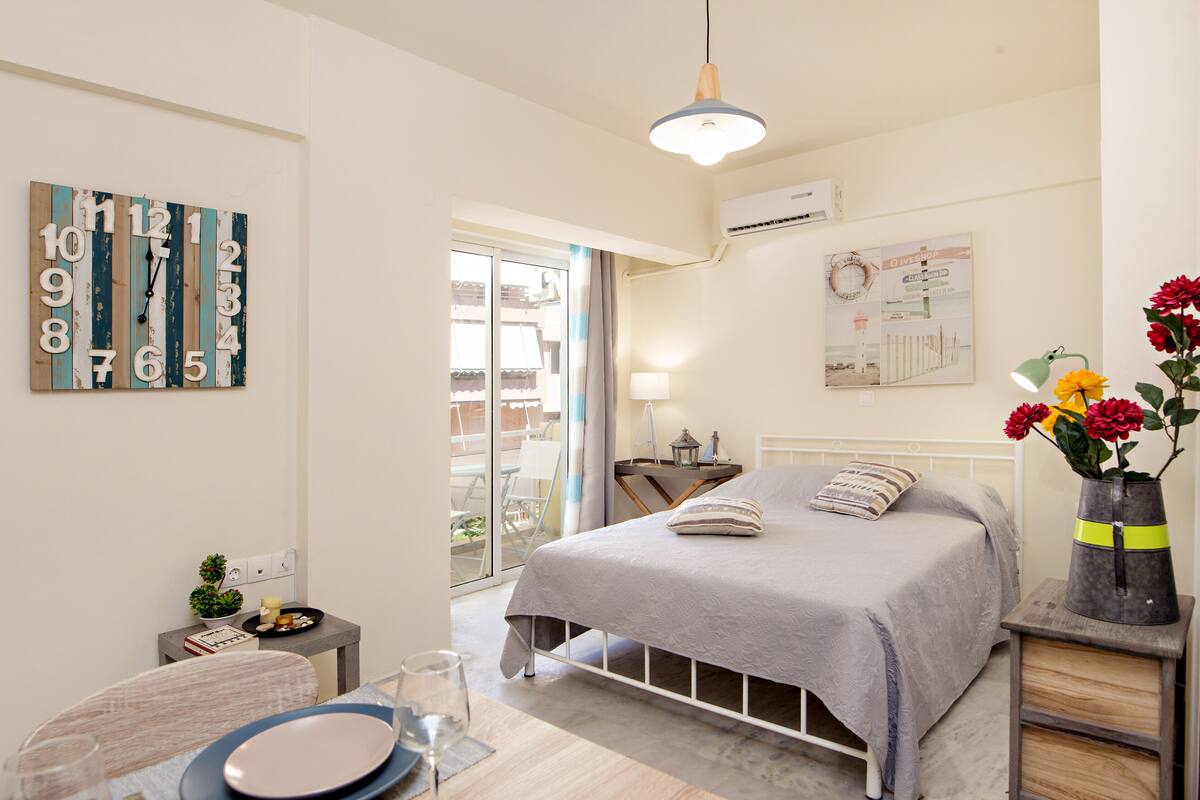 A bedroom with a bed, bedside table, lamp, and a wall clock.