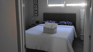Une chambre à coucher avec un lit, une table de chevet, une lampe et une fenêtre.