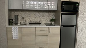Une cuisine moderne avec un dosseret de carreaux disposés en motif chevron, des appareils en acier inoxydable et des meubles de cuisine en bois clair.