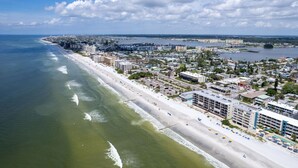 A coastal cityscape with a wide beach, buildings, and a marina. - Madeira Beach Getaway – Tropic Breeze 7 Pool View Condo (Madeira Beach)