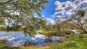 Un parc paisible avec un étang, des arbres et un ciel dégagé.