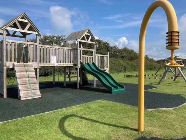 A playground with wooden structures, a slide, and a climbing area.