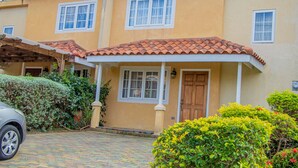 A two-story house with a tiled roof, a front porch, and a wooden door. - HOLIDAYS AT MANGO WALK COUNTRY CLUB (Montego Bay)