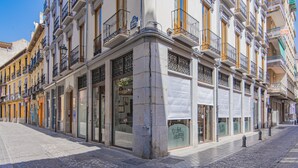 Vista de una calle con varios edificios y escaparates, incluyendo una tienda con un letrero que dice 'Los Artigos'.
