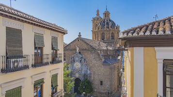 Una calle estrecha flanqueada por edificios, con balcones y un edificio histórico con cúpula y estatuas.