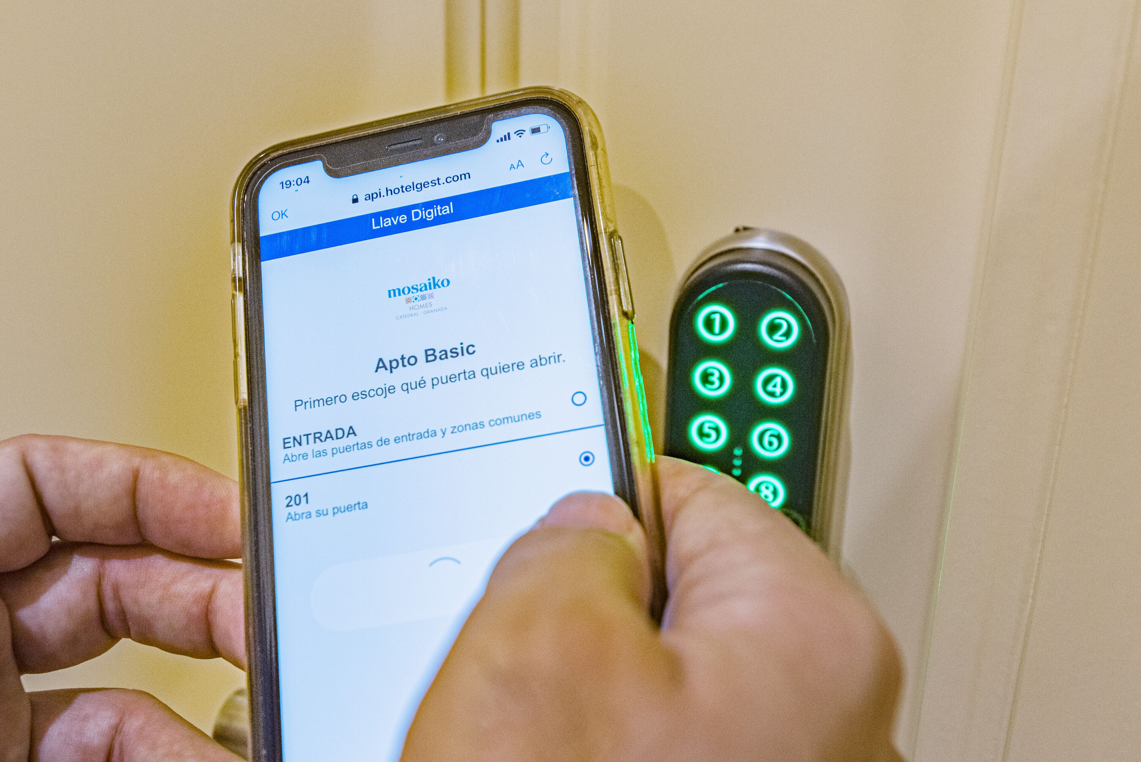 A person using a smartphone to interact with a digital hotel room keypad.