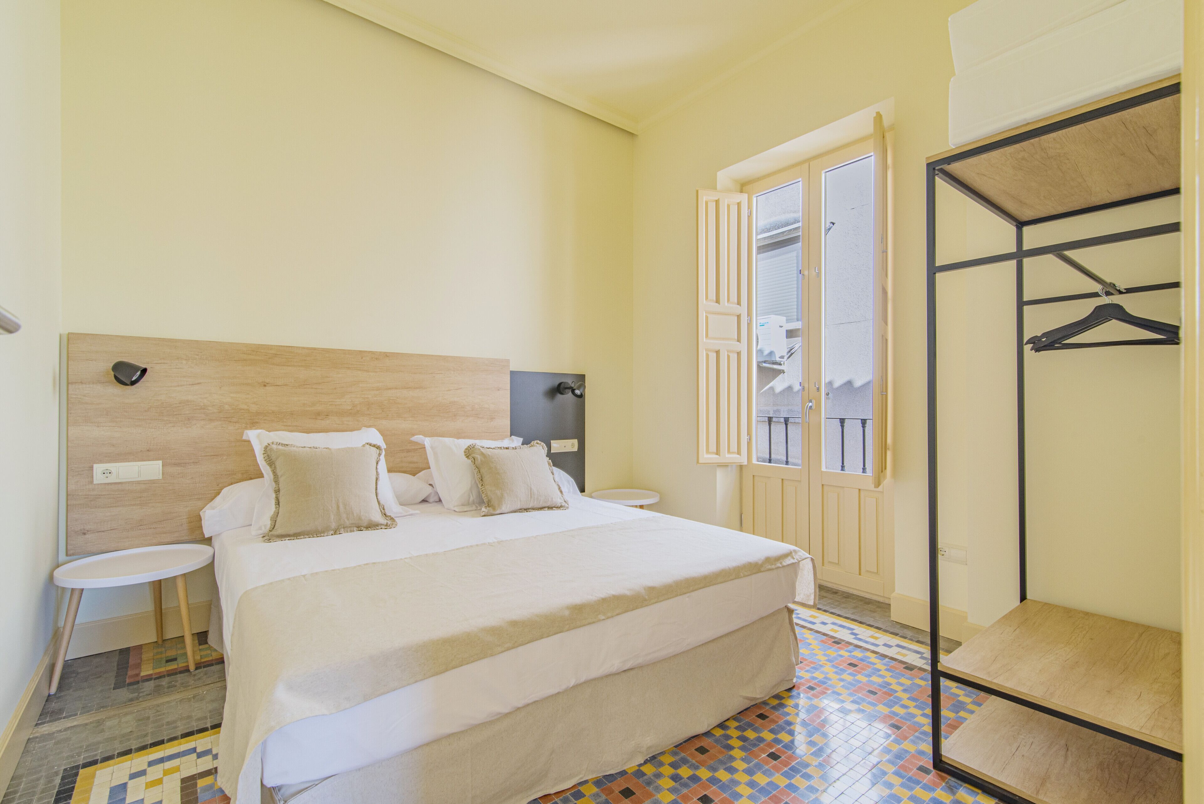 A bedroom with a bed, bedside tables, a window, and a metal wardrobe.