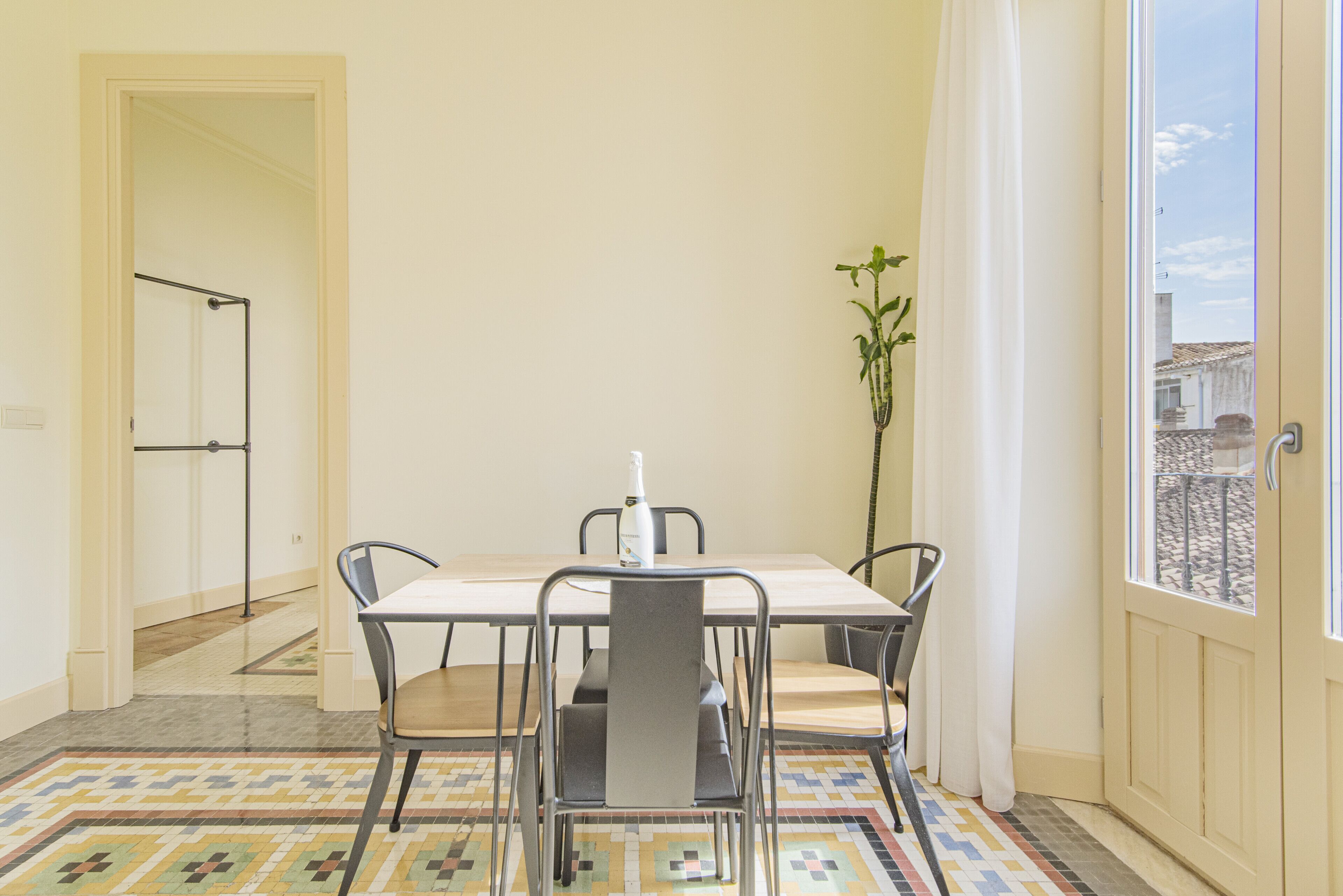 A dining area with a table and chairs, a potted plant, and a view through a door.