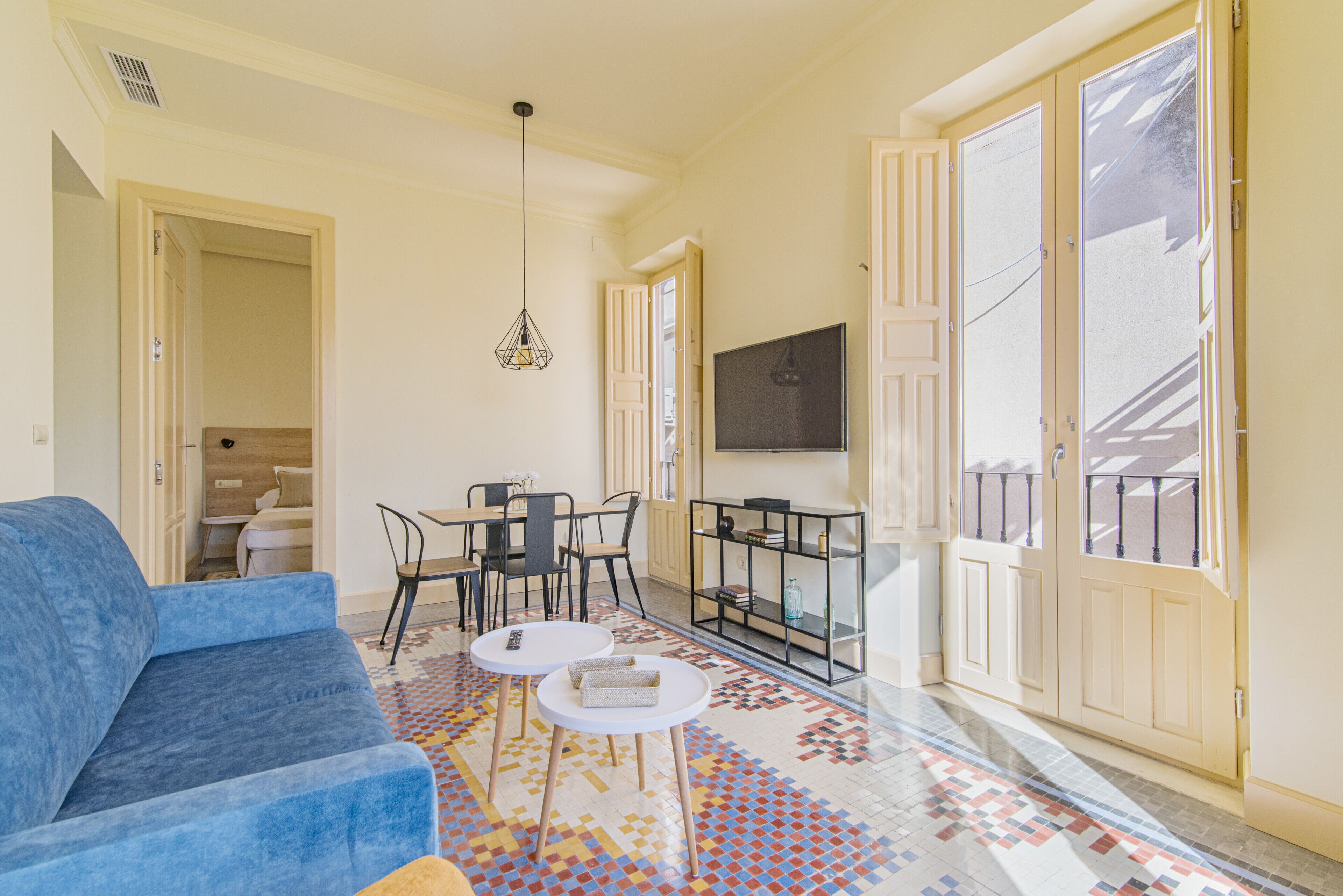 A living room with a blue sofa, two white round tables, and a patterned floor.