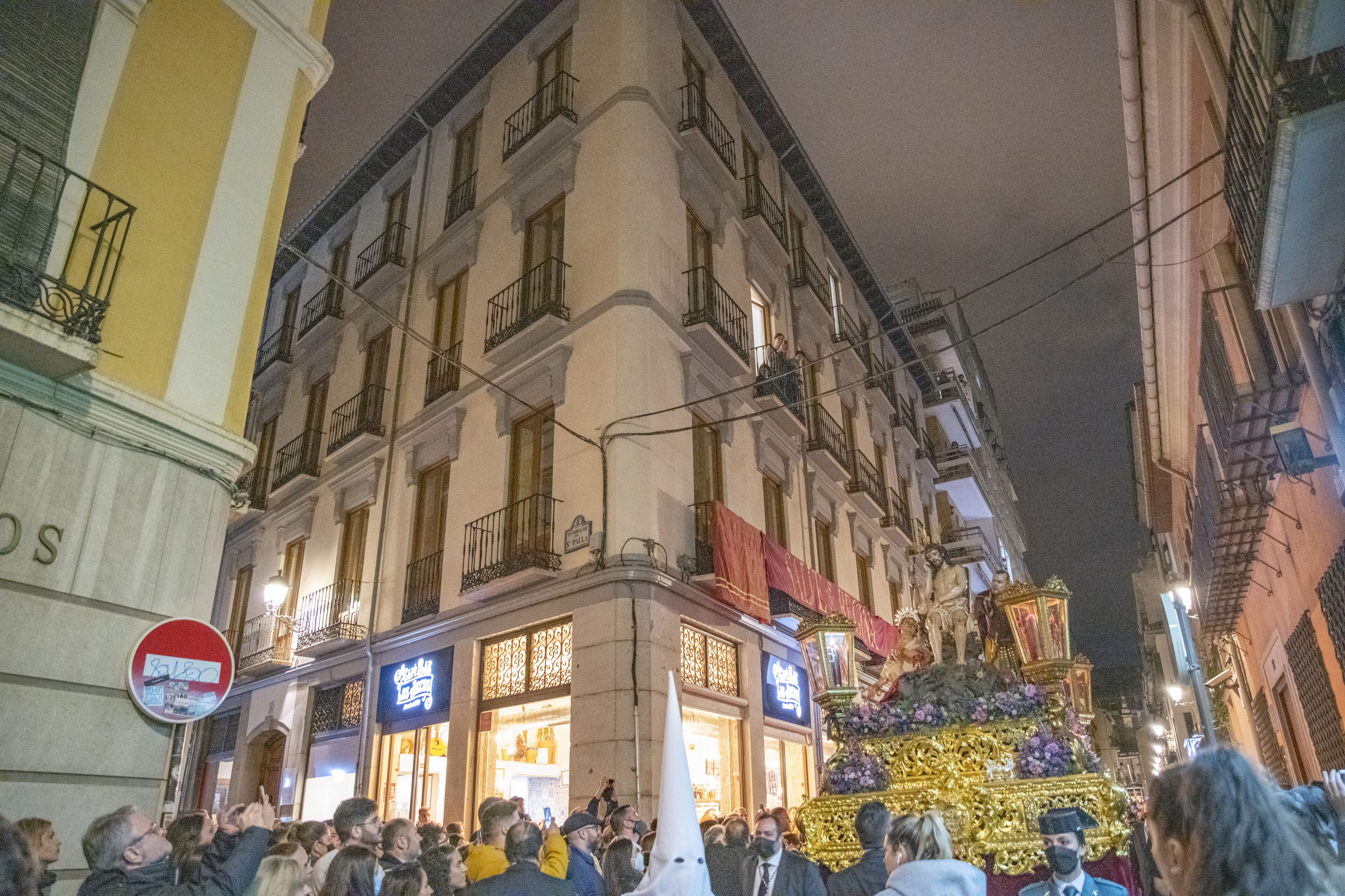 A crowded street scene with a building featuring a sign that reads "Café de la Paix."