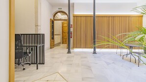 Una zona de recepción con un mostrador de madera, sillas de oficina negras y suelo de baldosas.