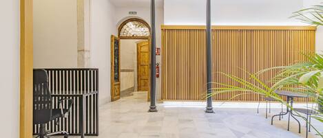 Uma área de recepção com balcão de madeira, cadeiras de escritório pretas e piso de azulejos.