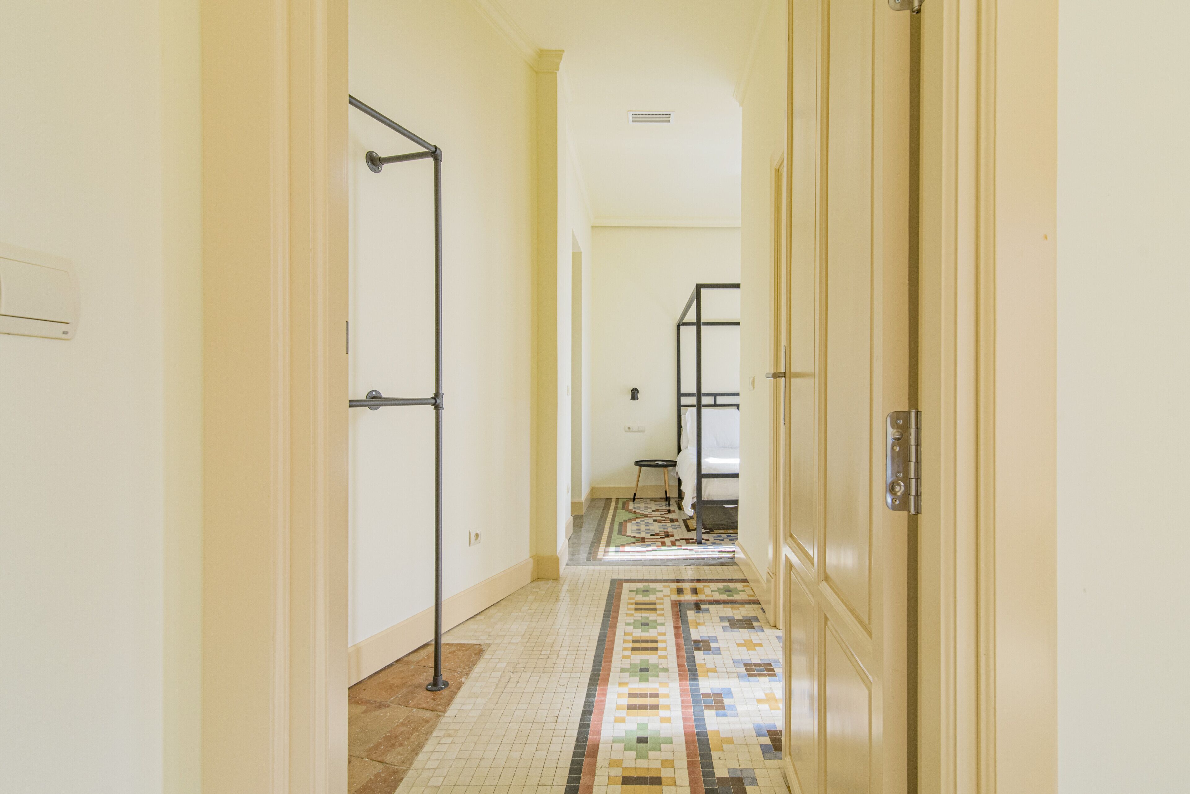 A hallway with tiled flooring, a metal rack, and a door with a handle.