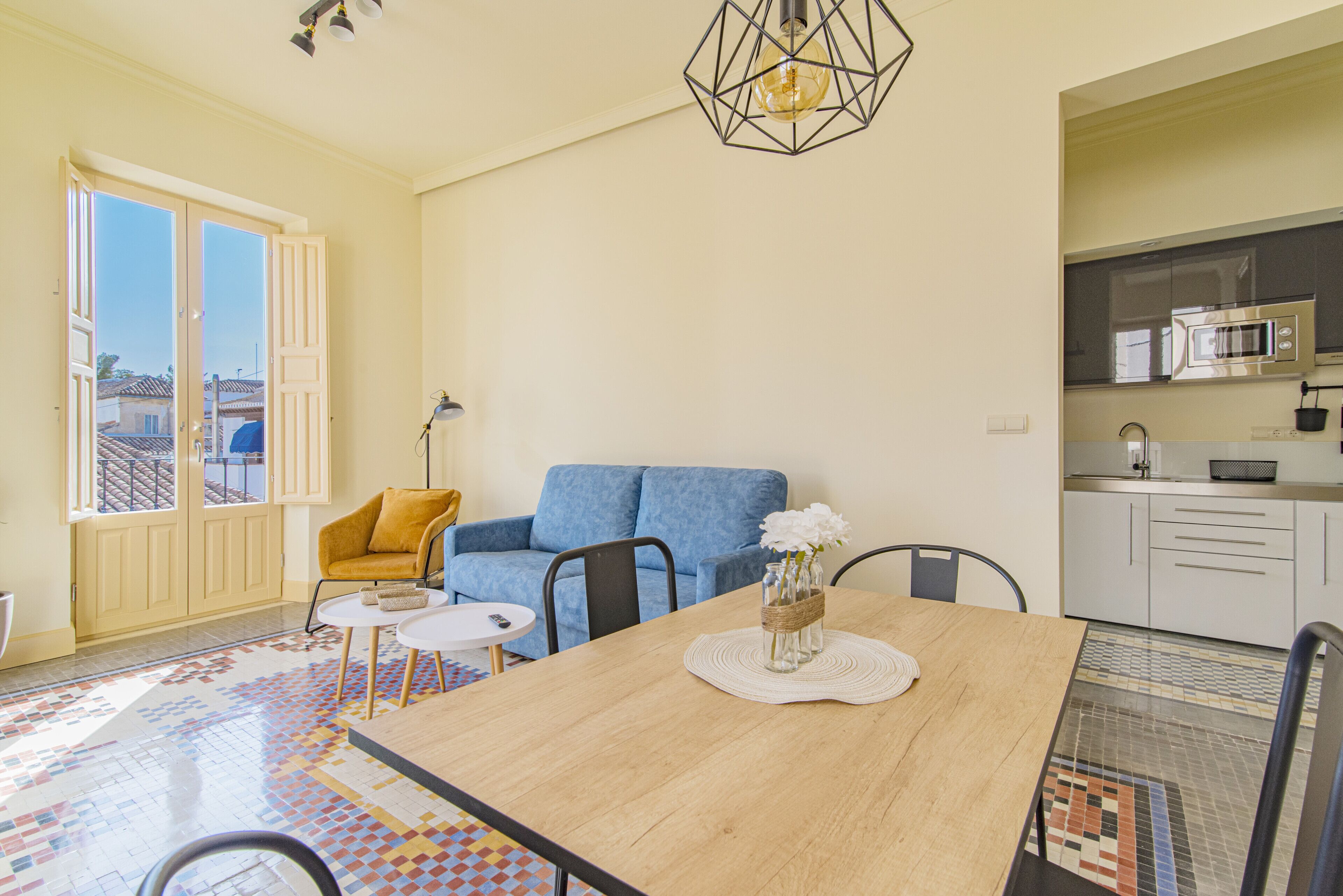 A modern living space with a dining area, a sofa, and a kitchen.