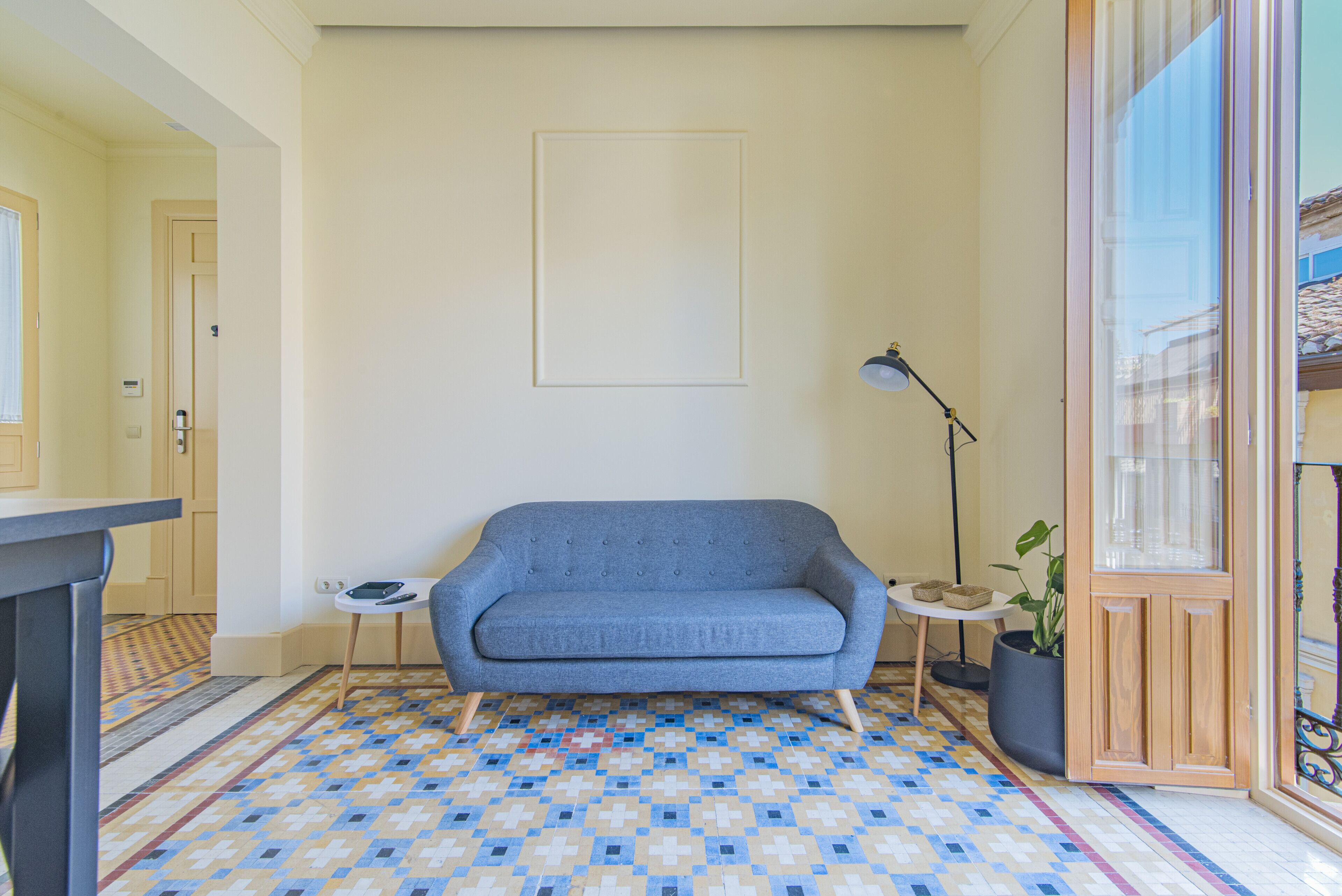 A room with a blue sofa, a small table, a lamp, and a potted plant.