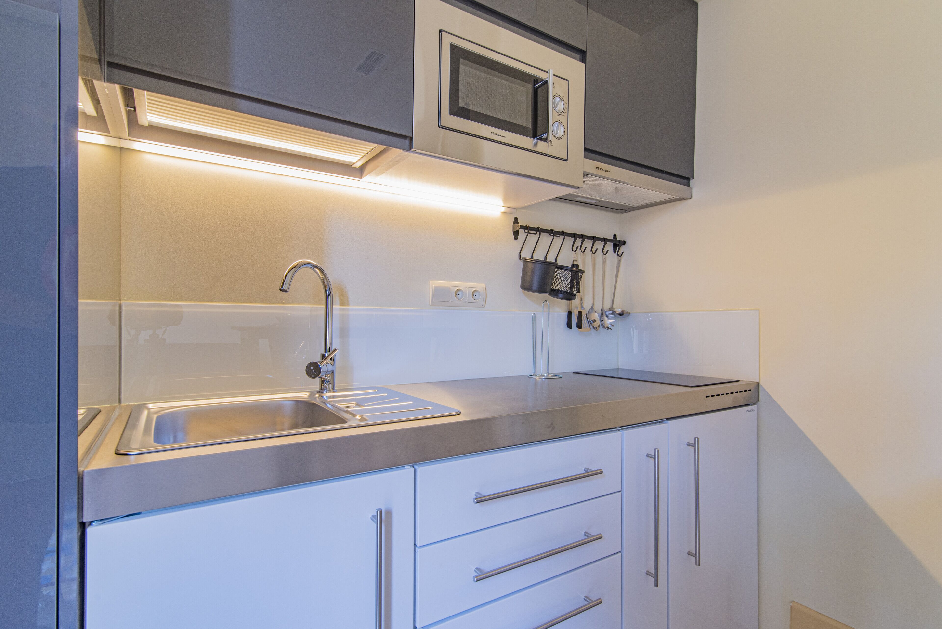 Een moderne keuken met een roestvrijstalen spoelbak, een magnetron en een pannendroger.