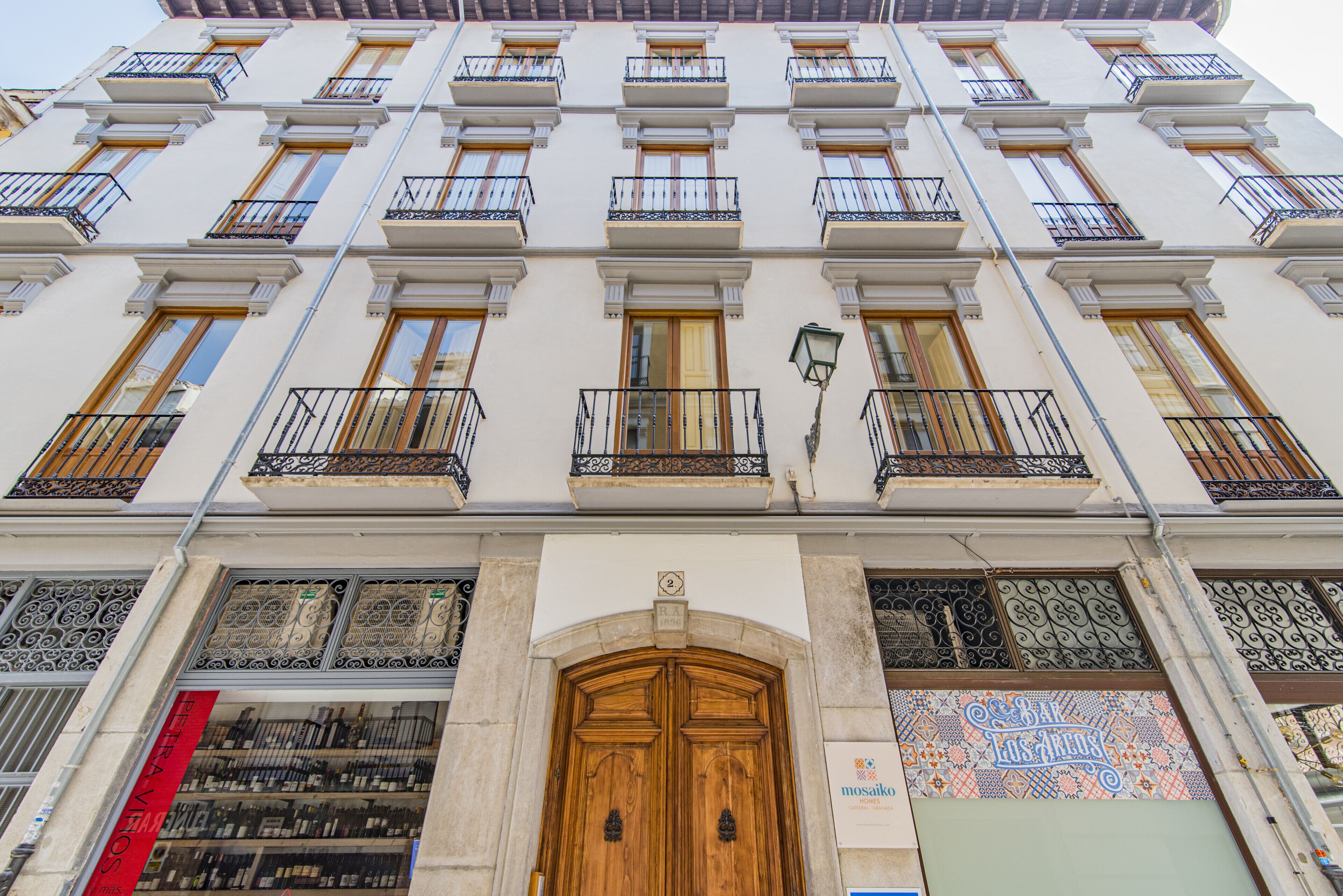 A multi-story building with a central entrance, balconies, and a sign indicating a bar.