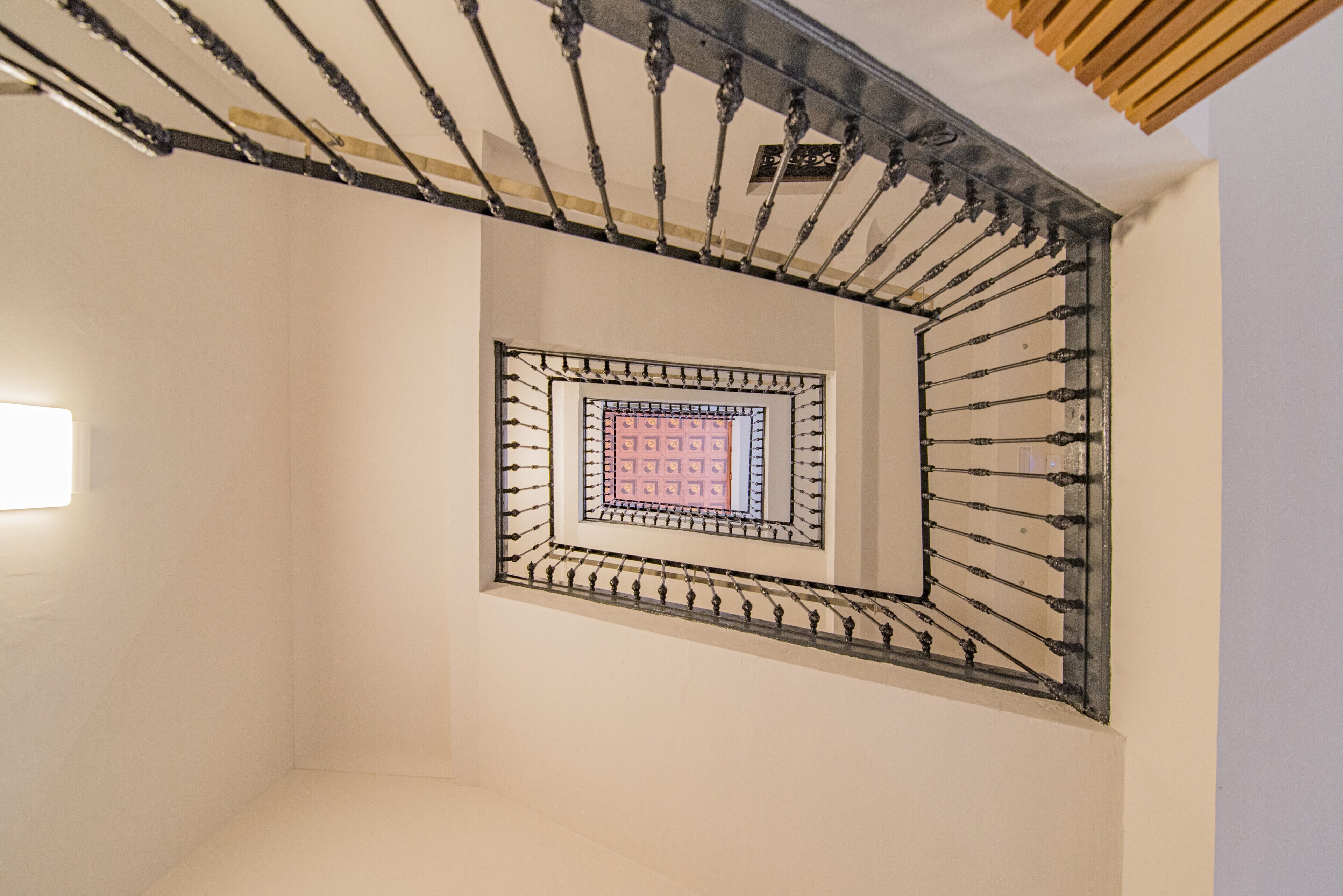A spiral staircase with a metal railing and a square window at the top.