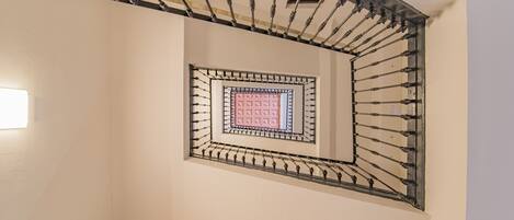 A spiral staircase with a metal railing and a square window at the top.