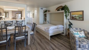 A compact room with a bed, a dining table with chairs, a kitchenette, and a small seating area with a couch. - Expansive Ocean Views-Prime Condo at Seascape! (Aptos)