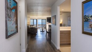 A spacious hallway with wooden flooring, a dining area with a view, and a kitchen area. - Expansive Ocean Views-Prime Condo at Seascape! (Aptos)