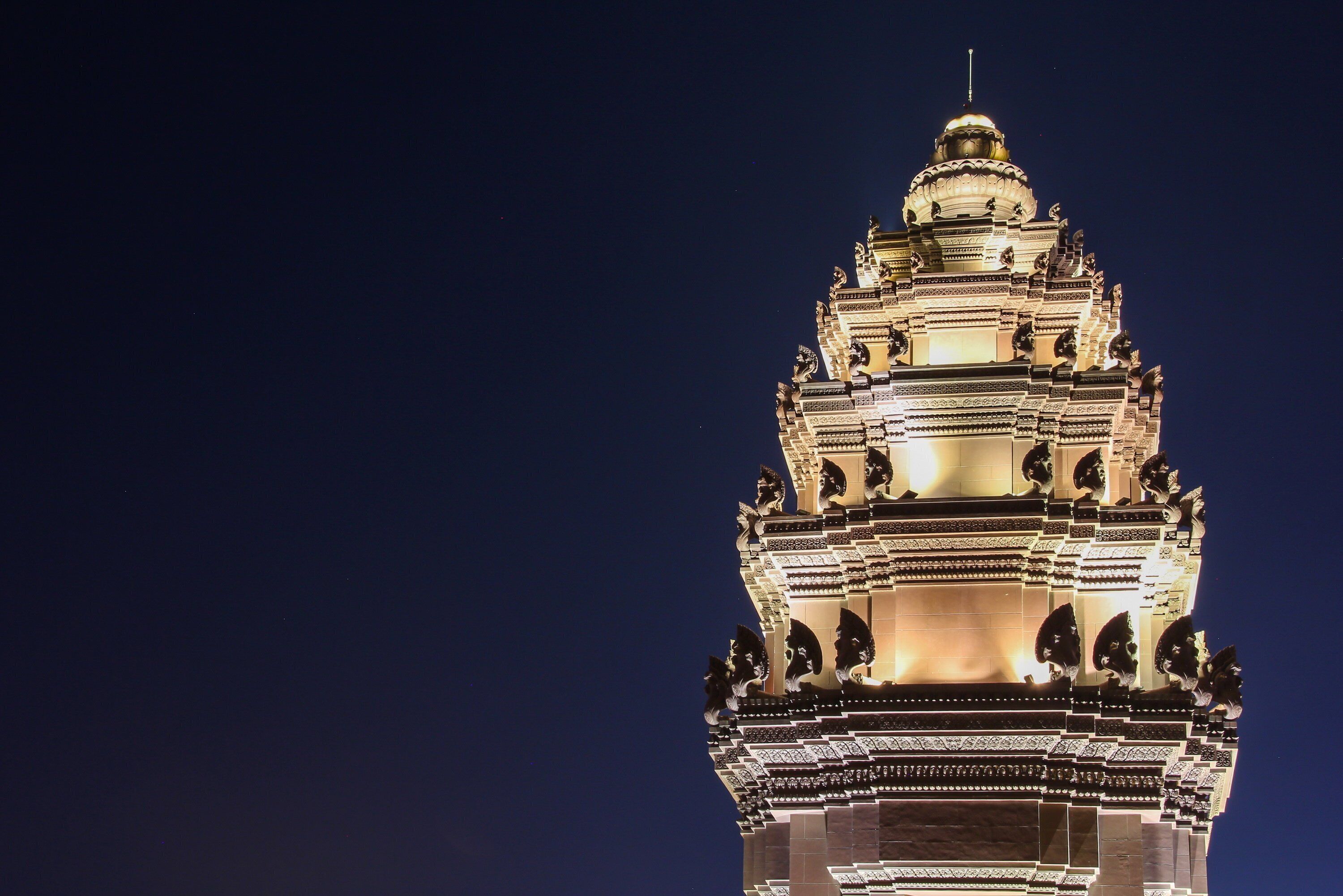 A night view of a temple with intricate architecture and a reflection on the water.