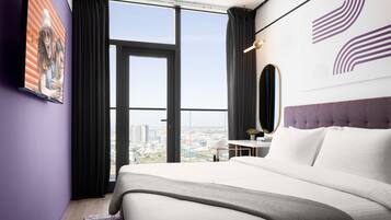 Een moderne hotelkamer met een groot bed, een bureau en uitzicht op de stad.