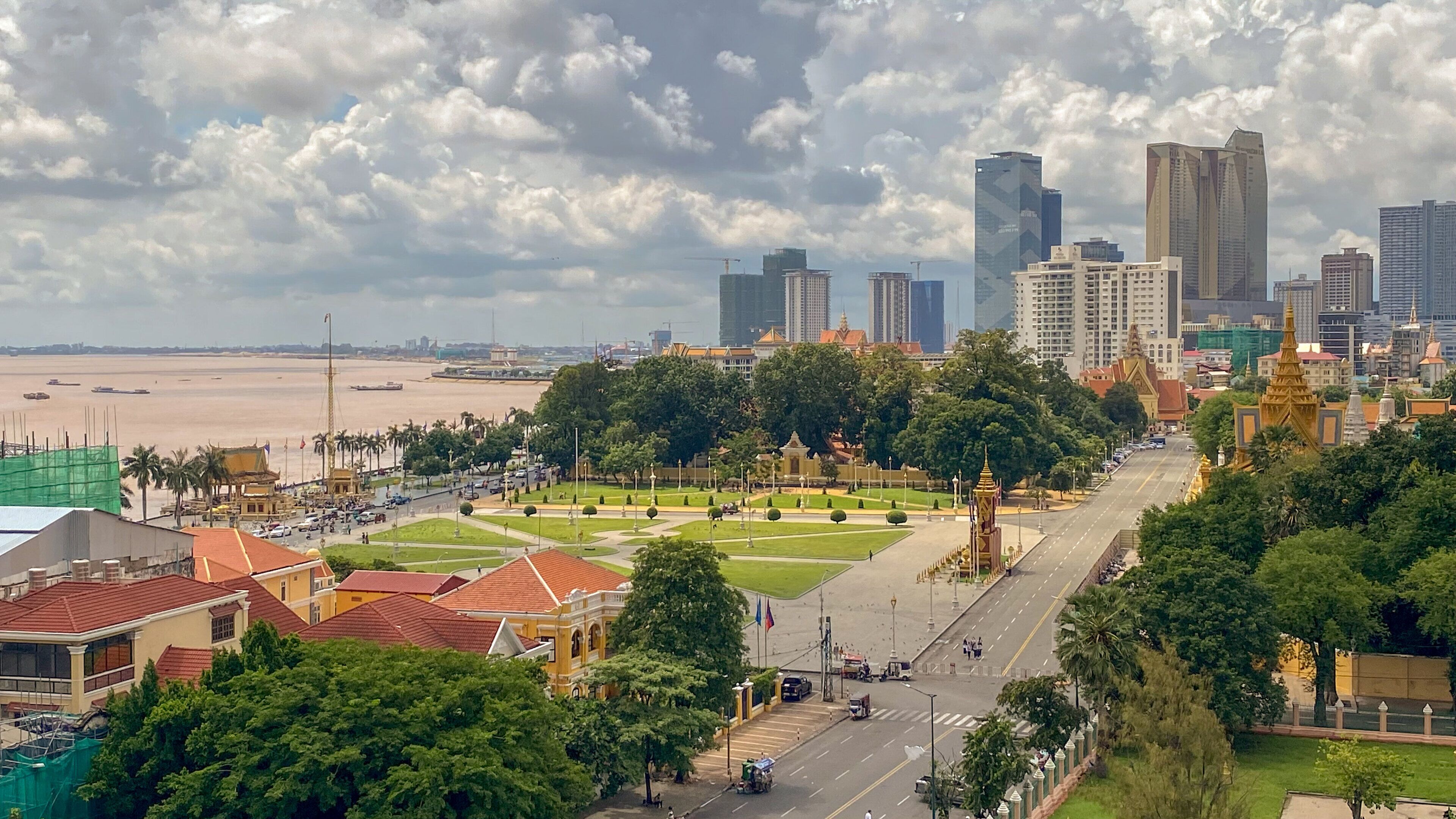 A cityscape with a river, modern buildings, and a park with traditional architecture.