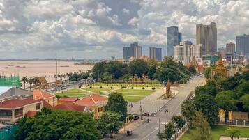 A cityscape with a river, modern buildings, and a park with traditional architecture.