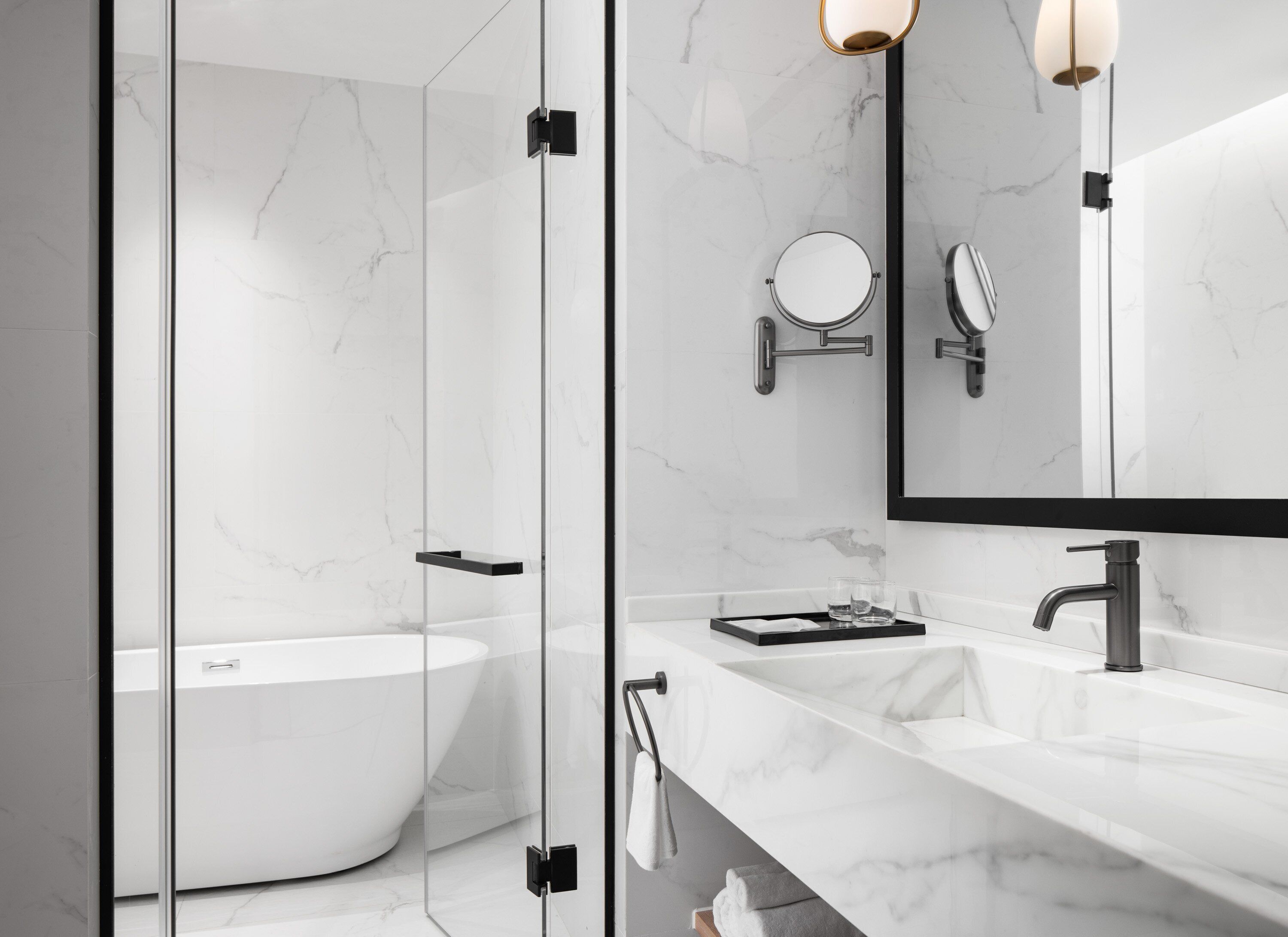 Un bagno moderno con cabina doccia in vetro, una vasca freestanding e un mobile vanità con uno specchio grande.