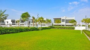 A modern building complex with a well-maintained lawn and trees. - Luxurious 3 Bedrooms with Maid room Villa (دبي)