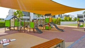 A playground with a slide, climbing structures, and a bench. - Luxurious 3 Bedrooms with Maid room Villa (دبي)